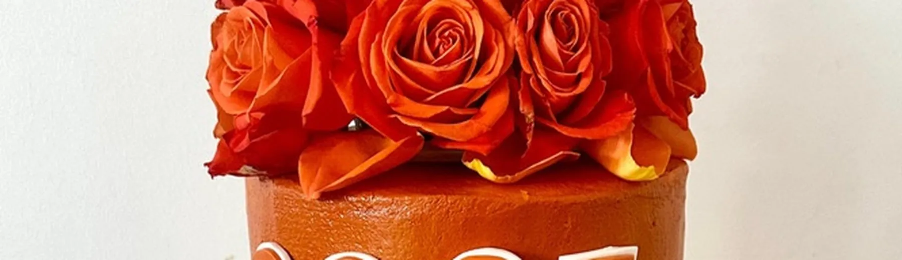 Burnt orange graduation cake topped with orange roses
