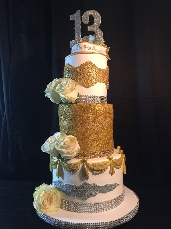 Four-tier 13th birthday cake with gold lace, white sugar roses and rhinestone bands