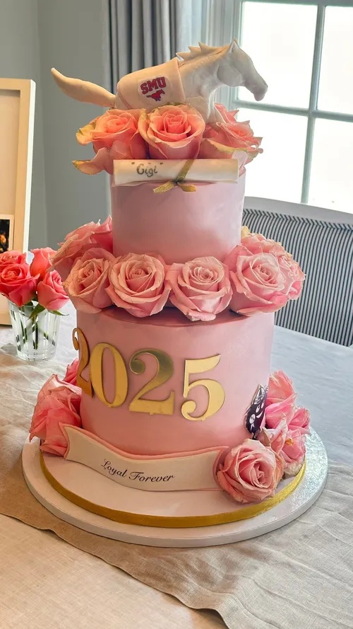 Pink two-tier SMU 2025 graduation cake with roses and a sculpted mustang topper