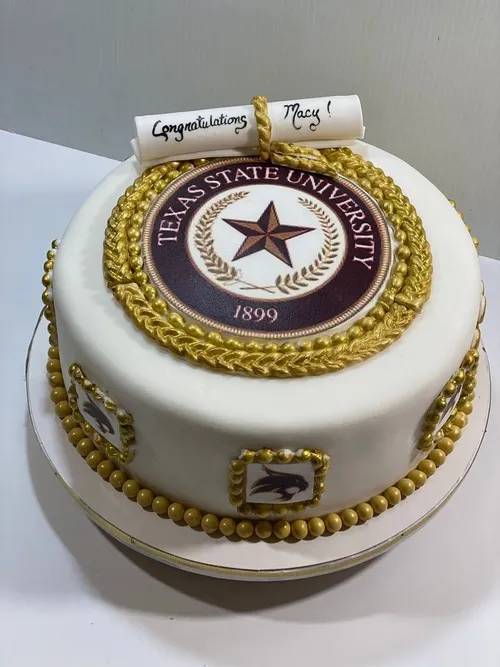 Texas State University seal graduation cake with gold beading and a diploma topper